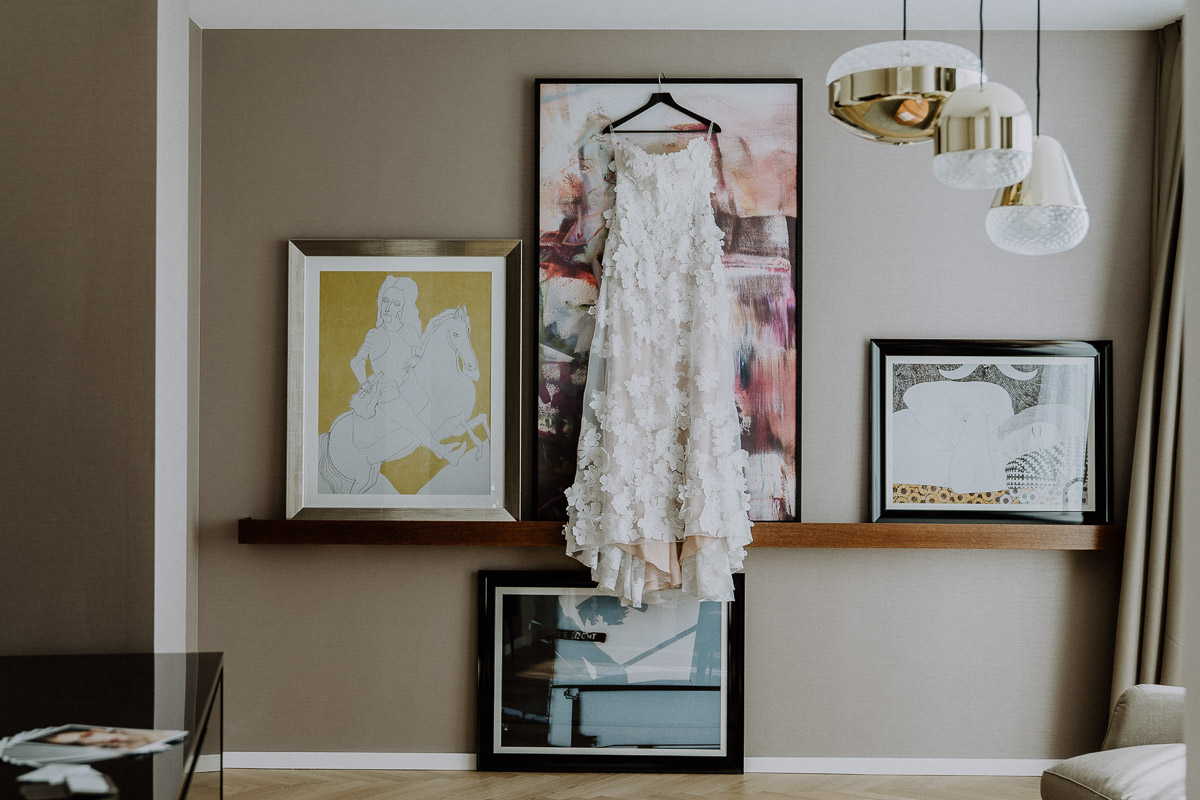 ein Brautkleid hängt im Andaz Vienna Hotelzimmer während Getting Ready der Braut by Kamerakinder Weddings