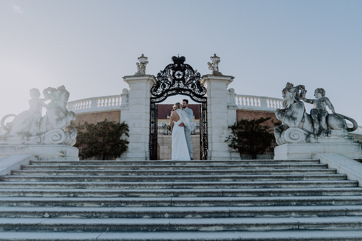 Brautpaar steht vor Schloss Hof und umarmt sich beim Sonnenuntergang After-Wedding-Shooting